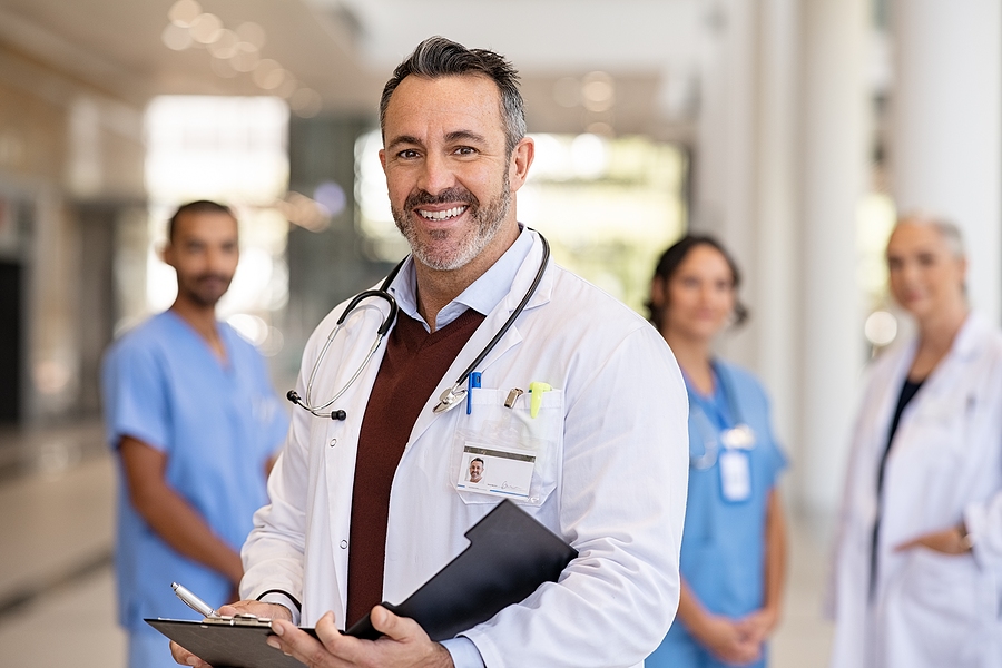 Smiling doctor standing in front of hospital staff.