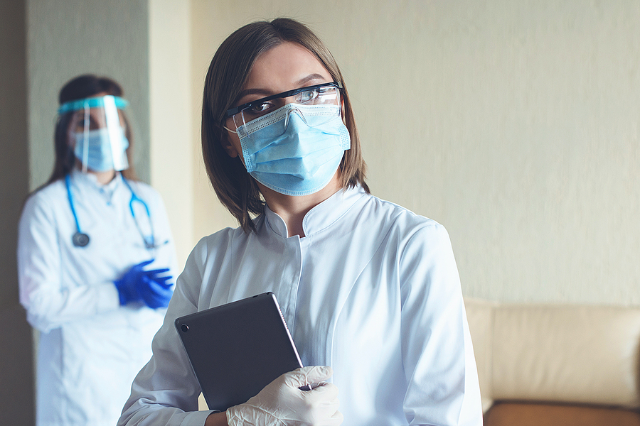 Healthcare staff at work wearing PPE and holding a tablet.
